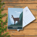Kartka pocztowa, nowoczesna grafika kozicy górskiej, stojącej na tle zielonych szczytów.  W oddali błękit nieba.  Na dole napis: kozica.