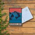 Kartka pocztowa z nowoczesną grafiką Morskiego Oka. Niebieskie szczyty, nad pomarańczowym niebem. Na dole tafla jeziora i napis Morskie Oko.