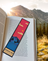 Zakładka z nowoczesną grafiką Morskiego Oka, wsadzona do książki. W tle widok na Tatry.