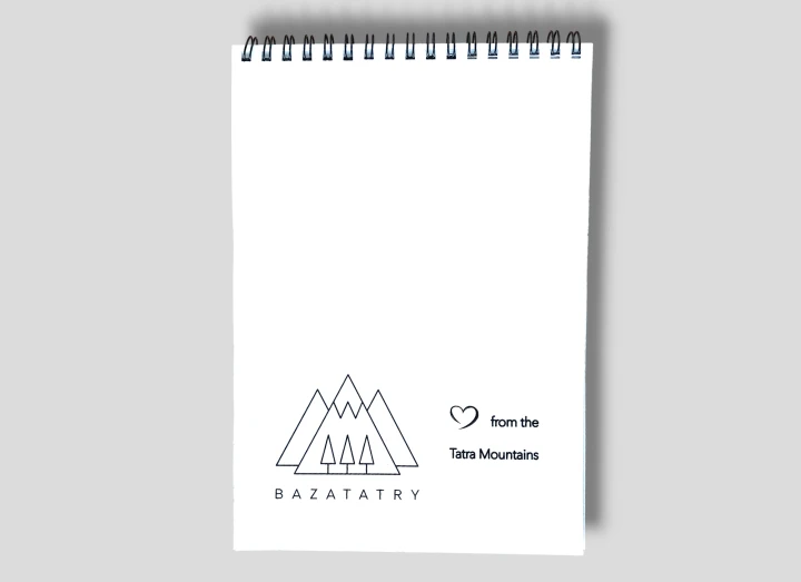 Tył notesu, na górze łączenie, spirala. Białe tło, na dole, logo firmy bazatatry. Trzy szczyty gór, a w nich trzy choinki. Obok serce i napis from the tatra mountains.