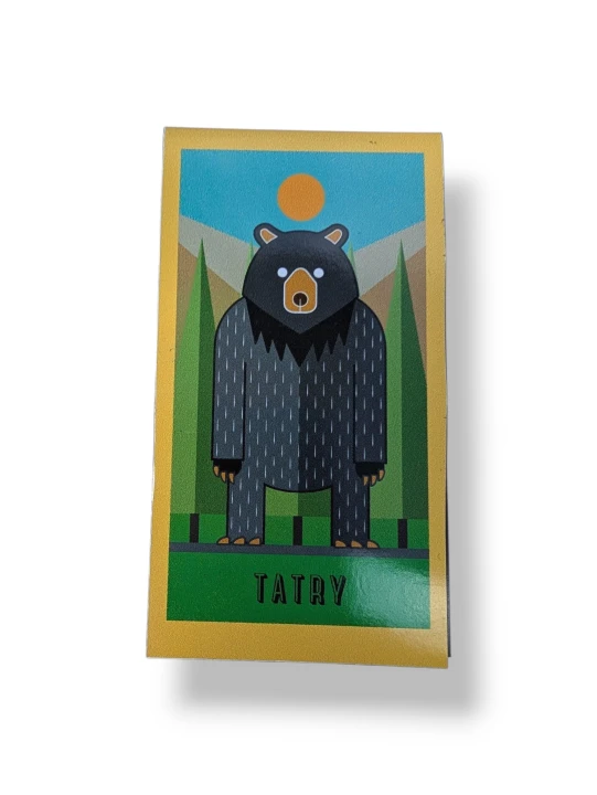 Zakładka magnetyczna.  Przedstawia nowocześna grafikę, stojącego na dwóch łapach niedźwiedzia. Na tle górskich lasów. Zimne kolory.